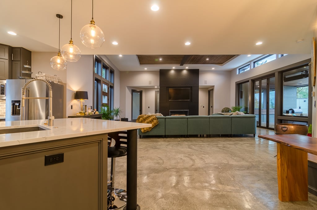 Large open living & dinning room with floor to ceiling black fireplace and green couch Large open living & dinning room with floor to ceiling black fireplace and green couch